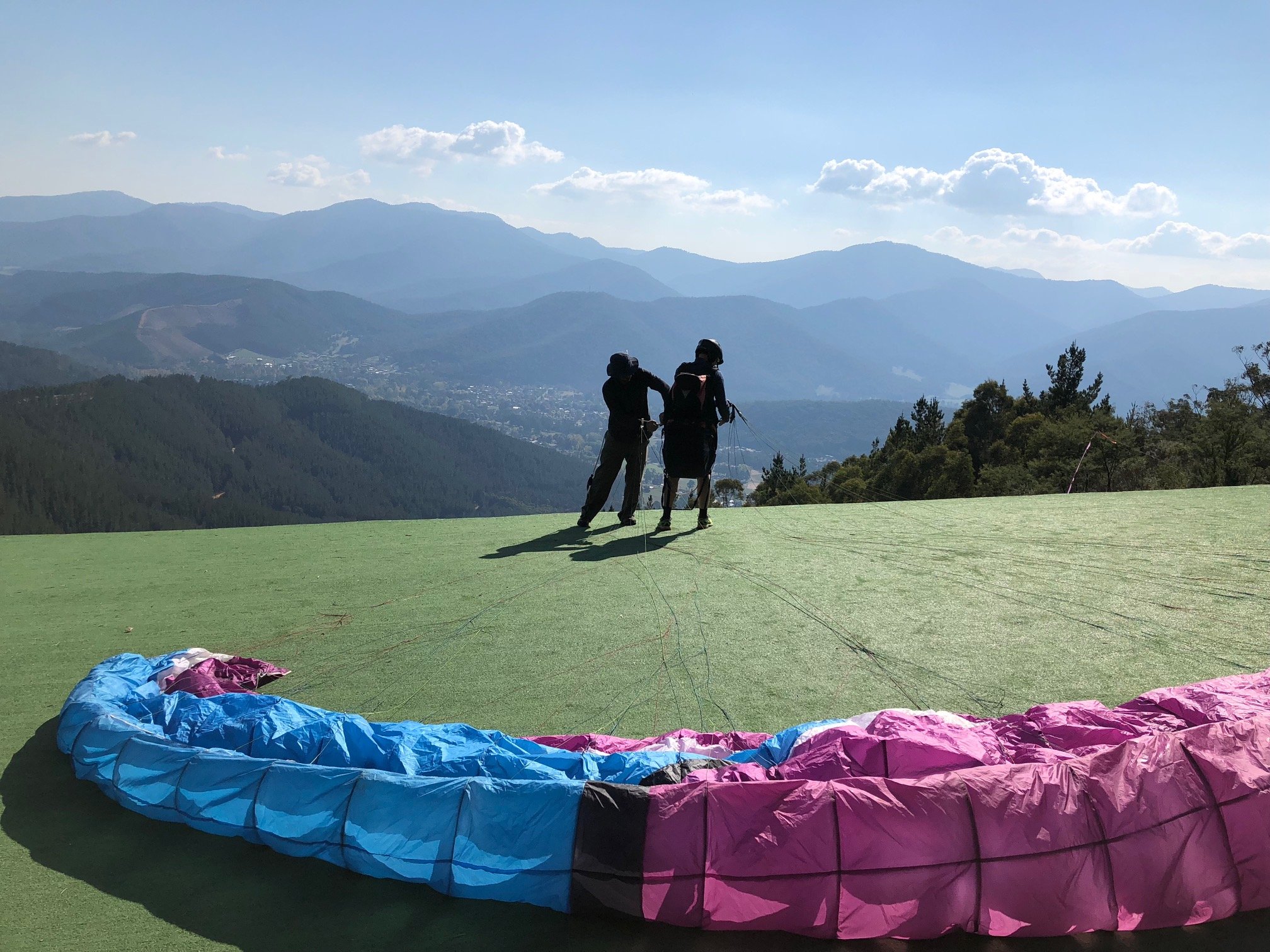 the paragliding instructor tying the belt of the novice flyer