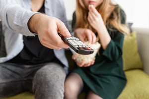 a-couple-sitting-on-the-sofa-and-watching-tv-while-eating-popcorn